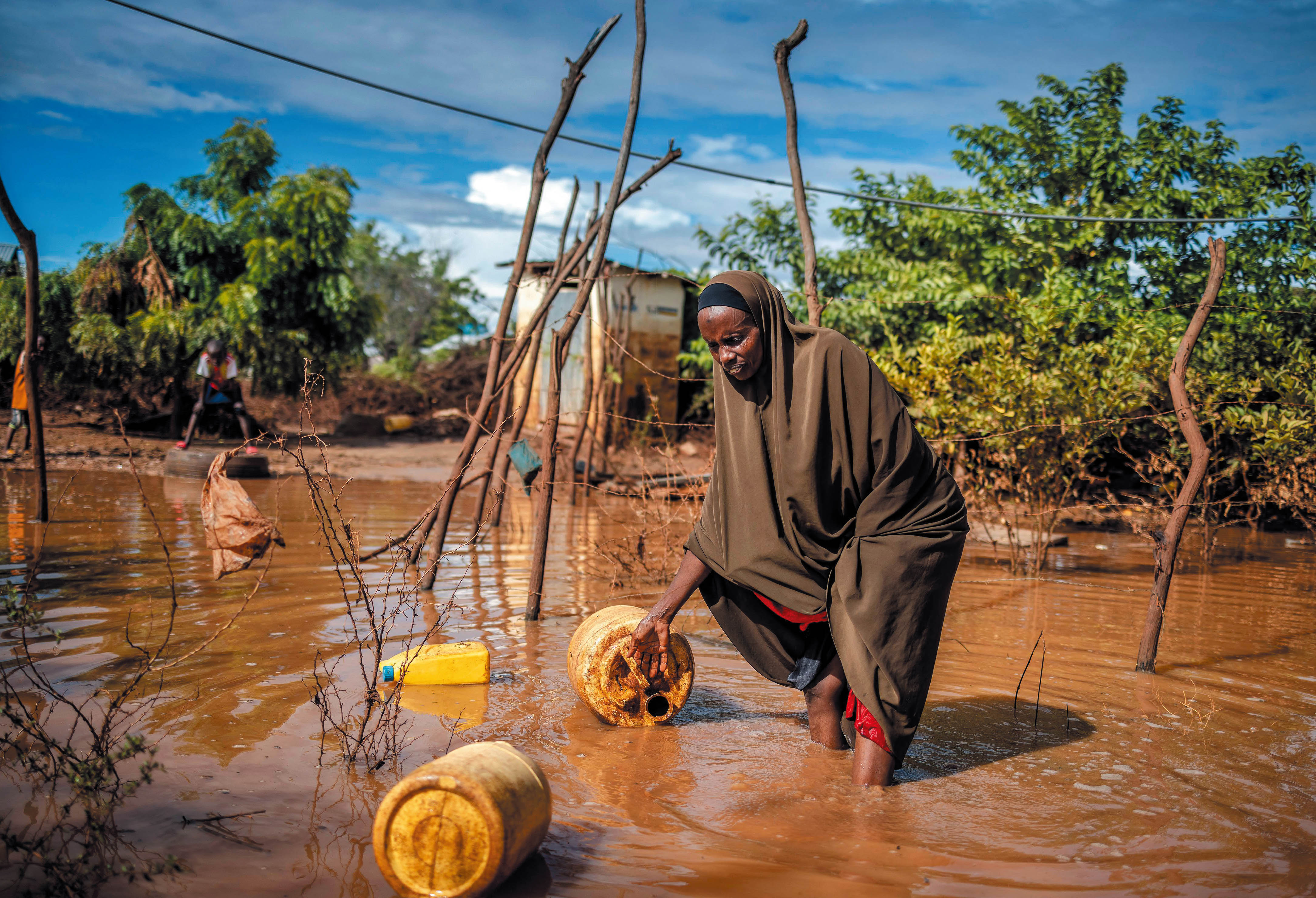 A woman in Kenya tries to collect some of her belongings after torrential rain led to heavy flooding. (credit: Luis Tato/AFP via Getty Images)